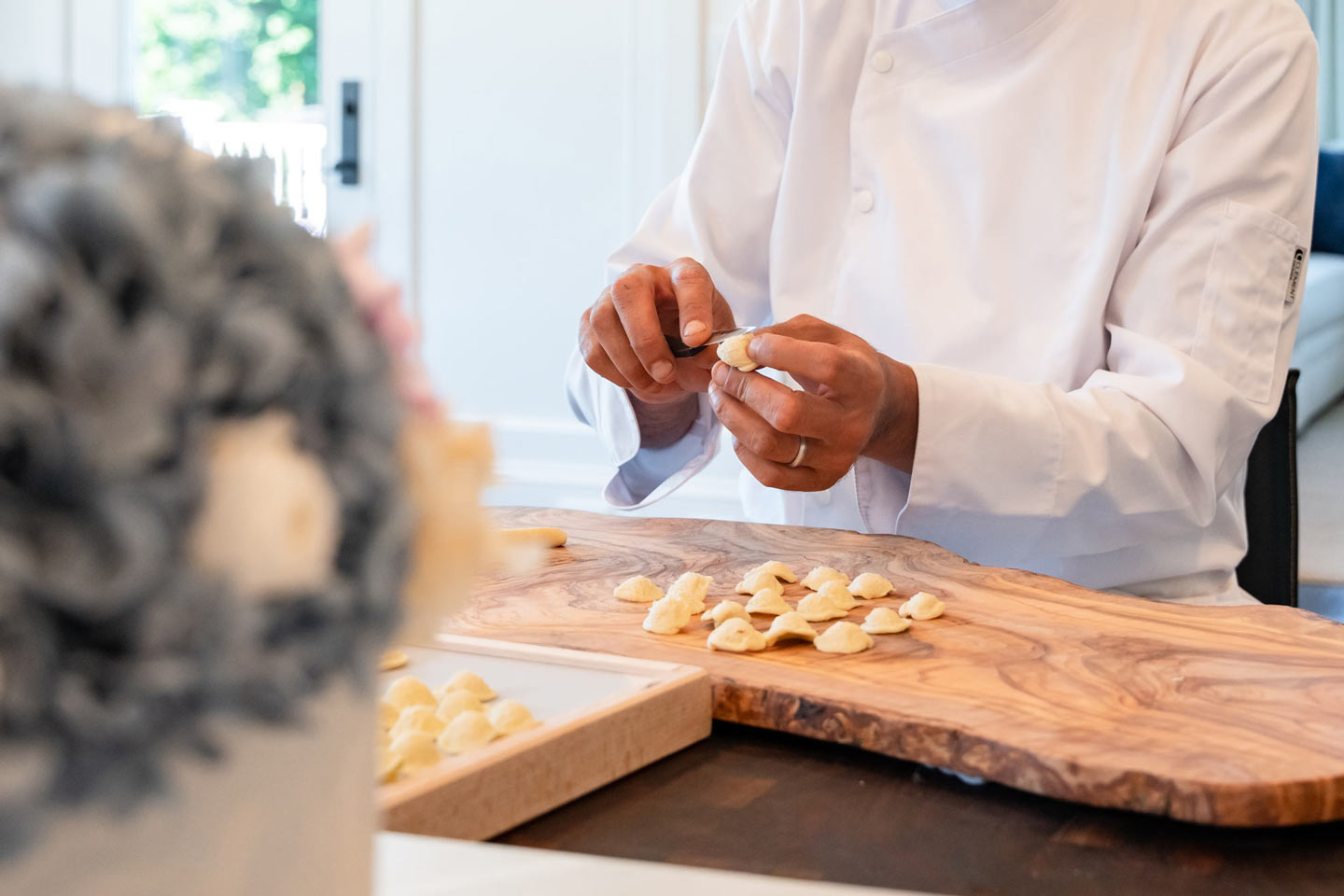 Chef preparing handmade pasta on a wooden cutting board, representing craftsmanship and high-end culinary web content.